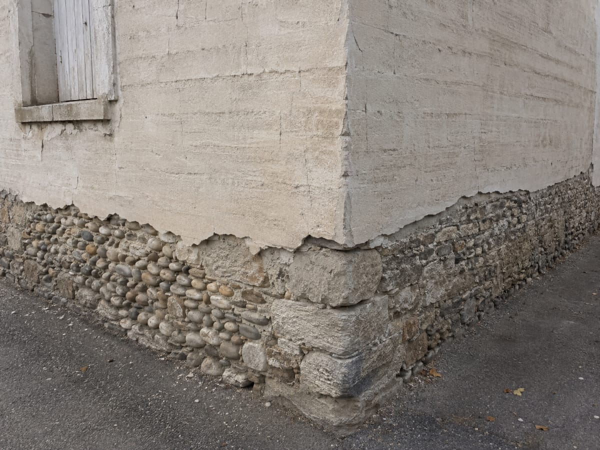 Détail d'une façade en pisé avec soubassement en pierre, typique du secteur de Trévoux et de la Dombes