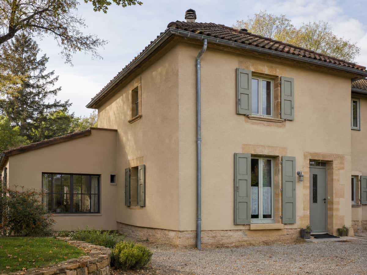 Détail d’une façade enduite montrant les encadrements, le soubassement et le raccord avec la toiture